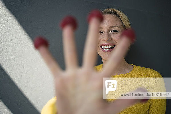 Blond woman with raspberries on her fingers  laughing