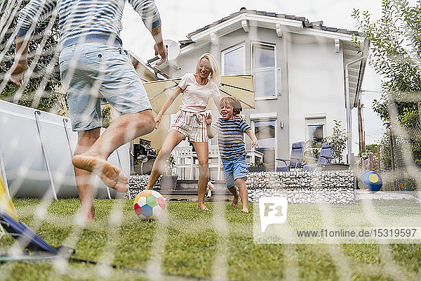 Happy family playing football in garden