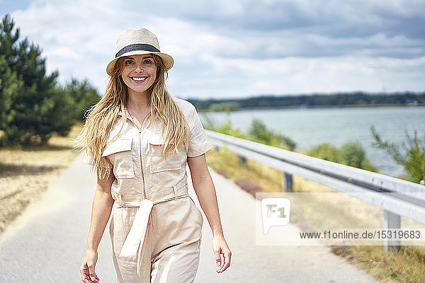 Portrait of smiling woman walking on rural road at the lakeside