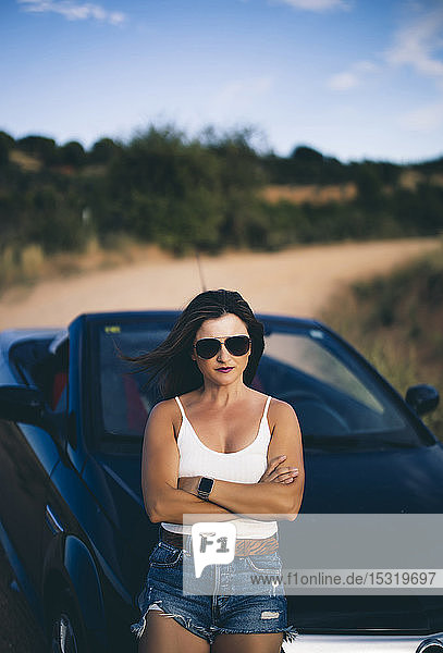 Sexy woman leaning on convertible  with arms crossed
