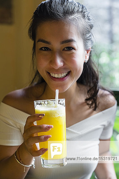 Porträt einer lächelnden jungen Frau  die einen Smoothie trinkt