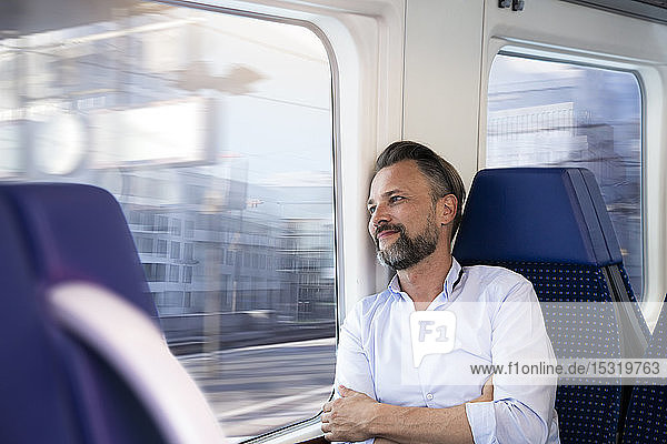 Mature man sitting in a train  looking out of window