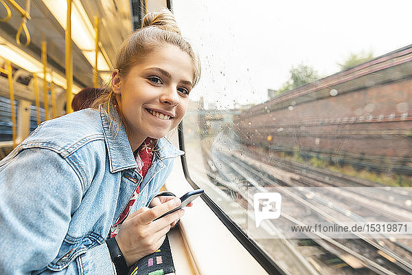 Porträt einer lächelnden jungen Frau  die mit dem Zug reist