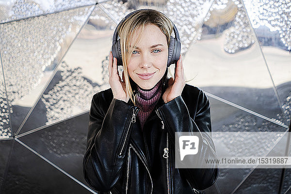 Portrait of smiling young woman listening music with wireless headphones