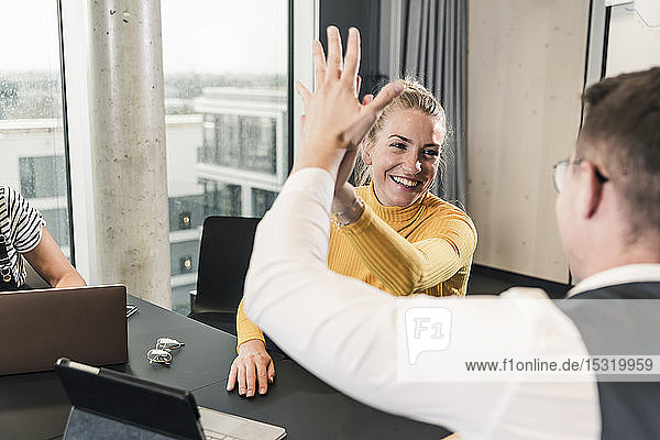 Happy businessman and woman high fiving in office