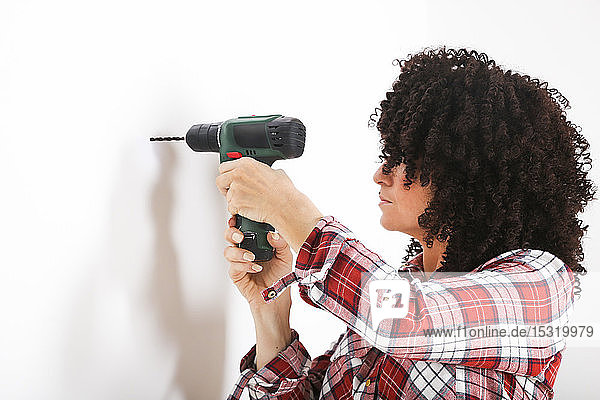 Woman using portable drill  marking with pencil on a wall