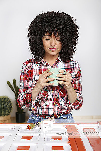 Frau  die zu Hause eine Tasse Kaffee hält  bemalte Möbel