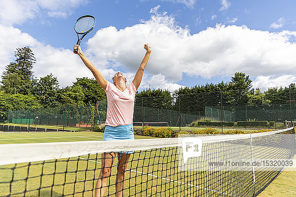 Glückliche Tennisspielerin feiert den Sieg auf Rasen