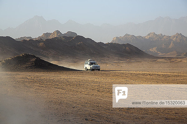 Geländewagen auf Staub in der Wüste gegen den Himmel bei Sonnenuntergang