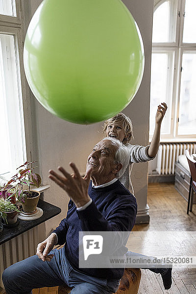 Glücklicher Großvater und Enkel spielen zu Hause mit dem Ballon