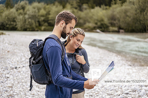 Young couple on a hiking trip reading map  Vorderriss  Bavaria  Germany
