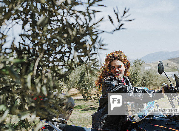 Porträt einer glücklichen rothaarigen Frau auf Motorrad  Andalusien  Spanien