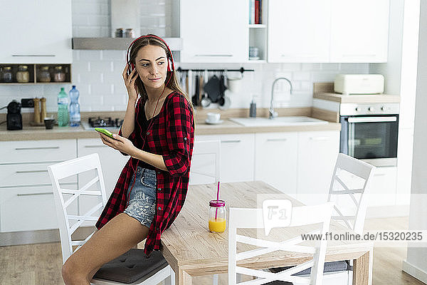 Young woman with cell phone and headphones at home