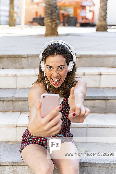 Junge Frau  die ein Smartphone benutzt  Musik hört und sich selbst eine