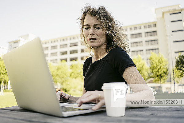 Porträt einer reifen Geschäftsfrau mit Kaffee zum Arbeiten am Laptop im Freien