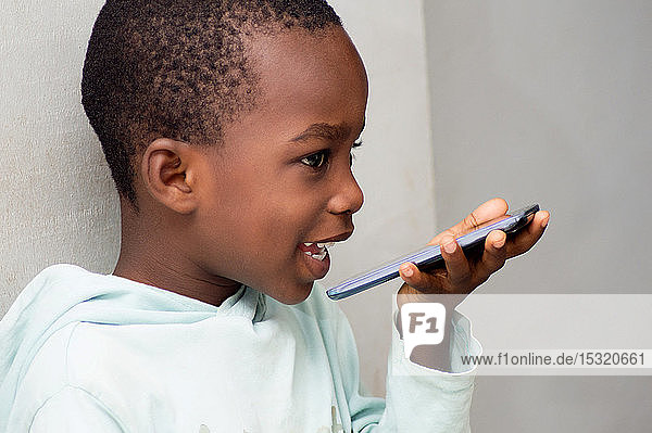 This child speaks directly into the microphone of the mobile phone along with a beautiful smile.