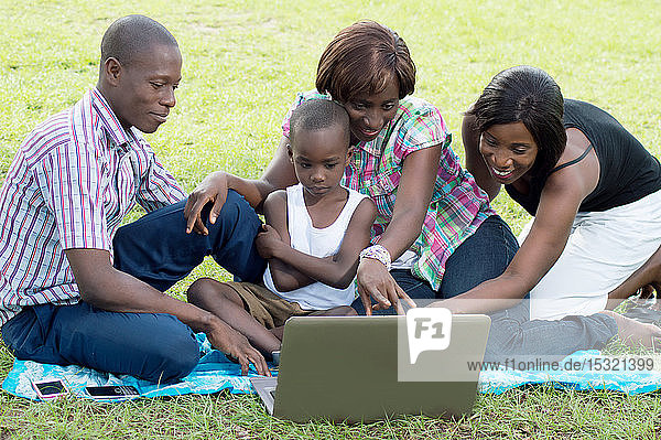 Eine Gruppe von Freunden und ein Kind schauen auf einen Laptop-Bildschirm.