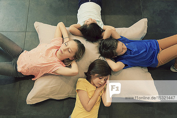 Vier Kinder schlafen auf einem großen Kopfkissen