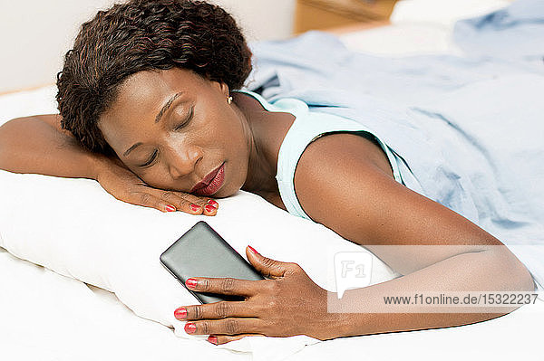 Beautiful woman sleeping in bed with her cell phone in her hand