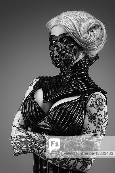 Portrait of a tattooed young woman wearing latex clothes and a gas mask