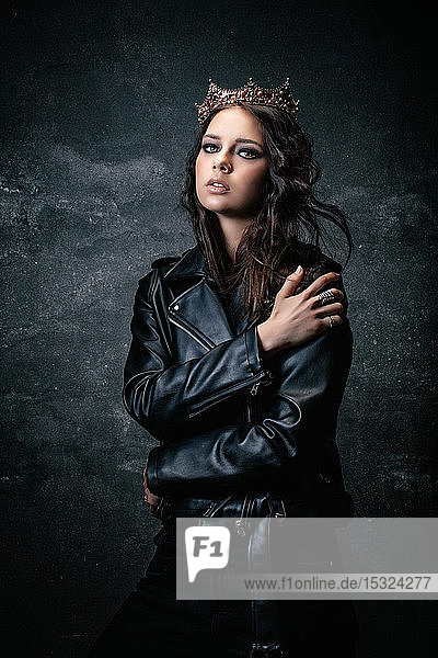 Young woman wearing a crown  a leather jacket  a hand on the shoulder