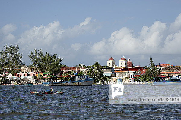 Cuba  Holguin area  the church and city of GIBARA from the sea where a fisherman stands in a very basic boat