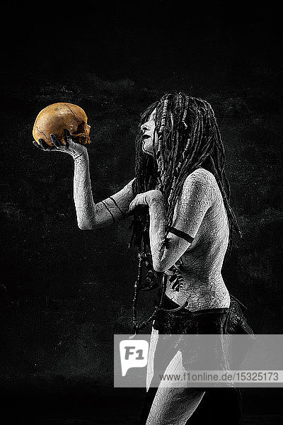 Porträt eines Schamanen  der einen menschlichen Schädel in den Händen hält