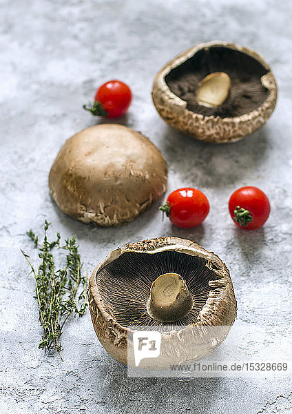 Rohe Portobello-Pilze  Thymianzweige und Kirschtomaten