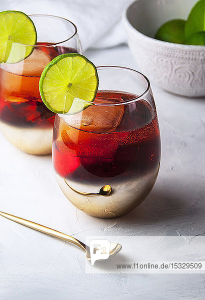 Zwei Gläser Aperol Spritz-Cocktail mit Limettenbeilage
