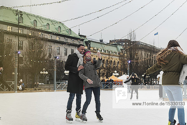 Couple taking selfie while ice skating