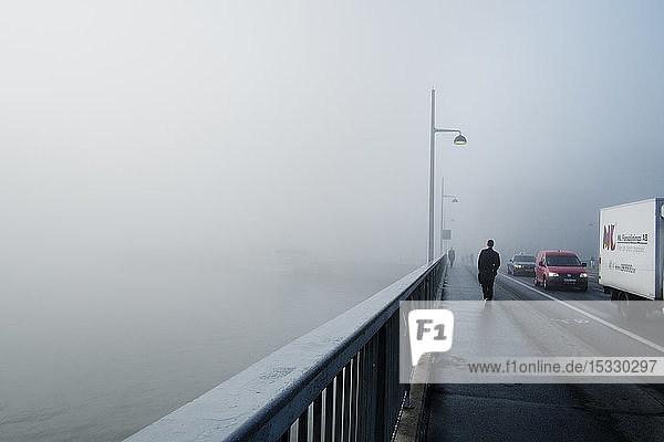 Man walking on bridge on foggy day in Stockholm