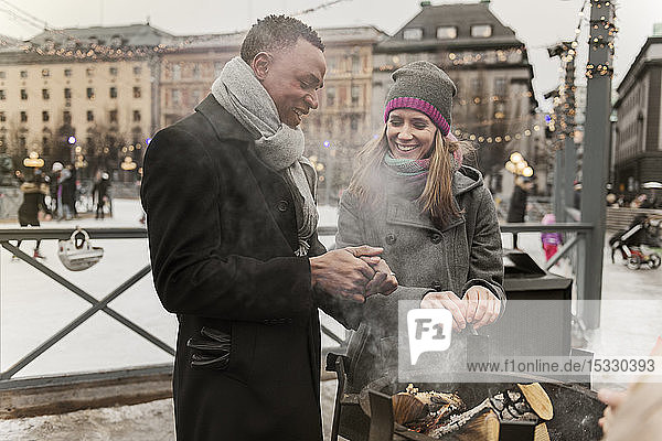 Couple warming their hands over fire