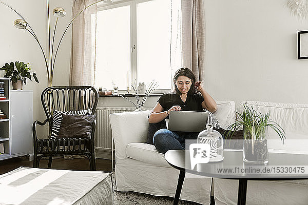 Young woman using laptop on sofa