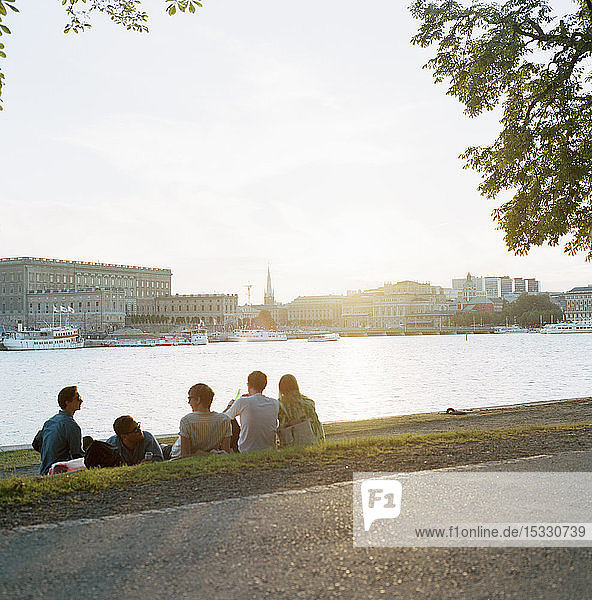Friends relaxing on riverbank at sunset