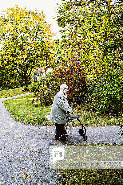 Senior woman using walking frame walking in park