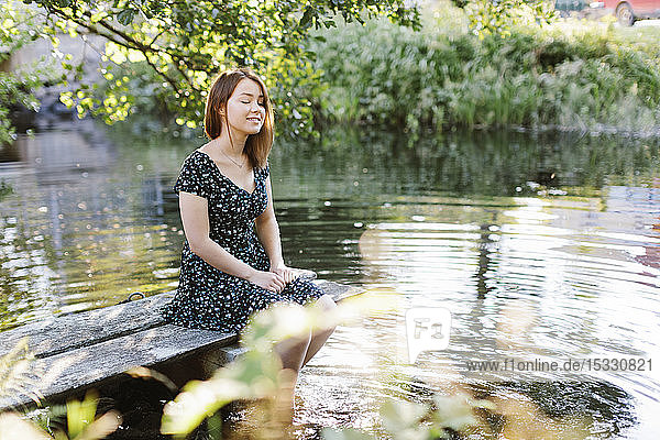 Young woman sitting by lake