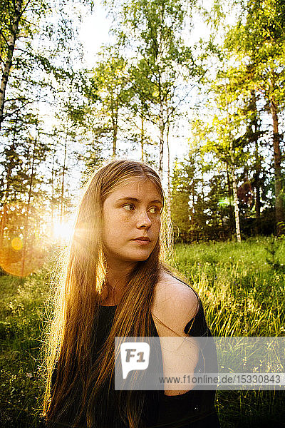 Portrait of young woman in forest at sunset