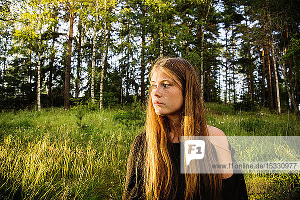 Portrait of young woman in forest at sunset