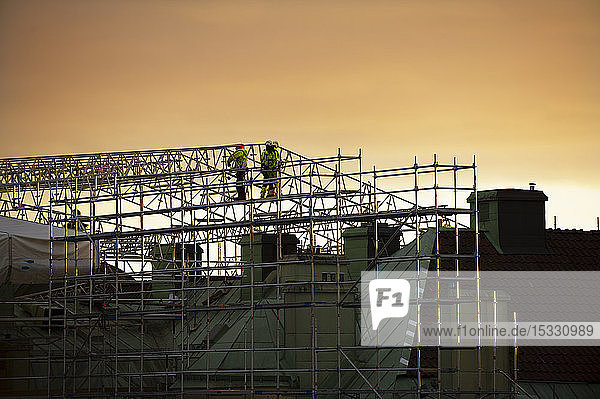 Bauarbeiter auf einem Baugerüst bei Sonnenuntergang