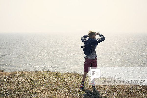 Junge mit Augenschutz auf einem Hügel über dem Meer