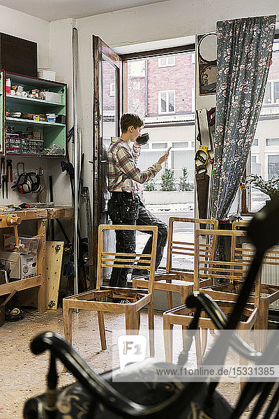 Carpenter using smart phone in workshop