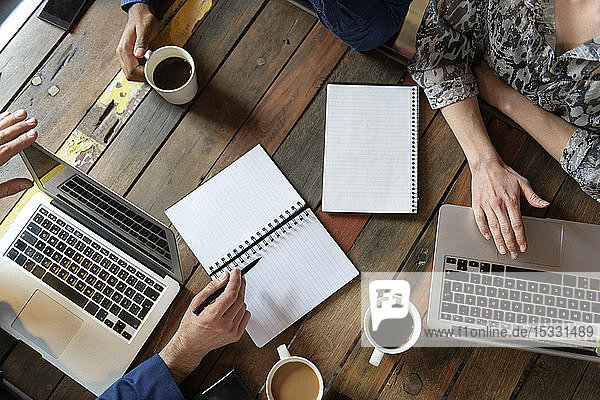 Arms of businesspeople on office table during meeting