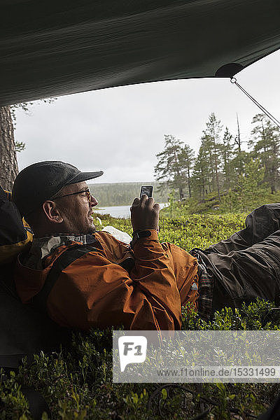 Man using smart phone in tent