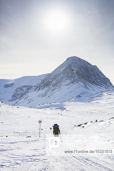 Frau beim Skifahren mit Markierungen auf der Kungsleden-Loipe in Lappland, Schweden