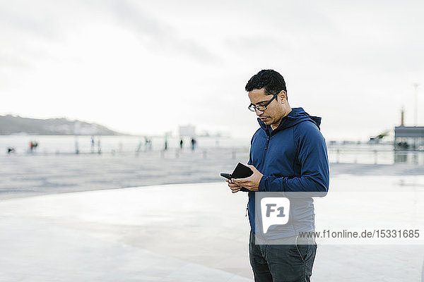 Man using smart phone in town square