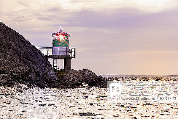 Lighthouse on rocks by sea during sunset in Kanholm Bay Sweden