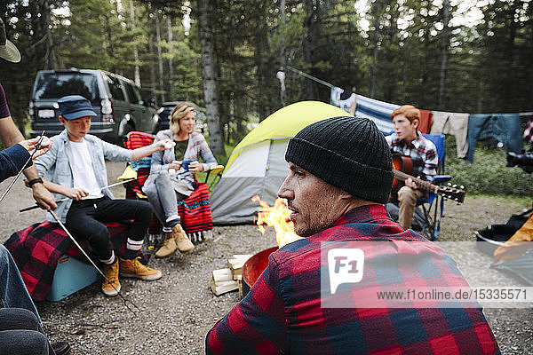 Family relaxing around campfire at campsite