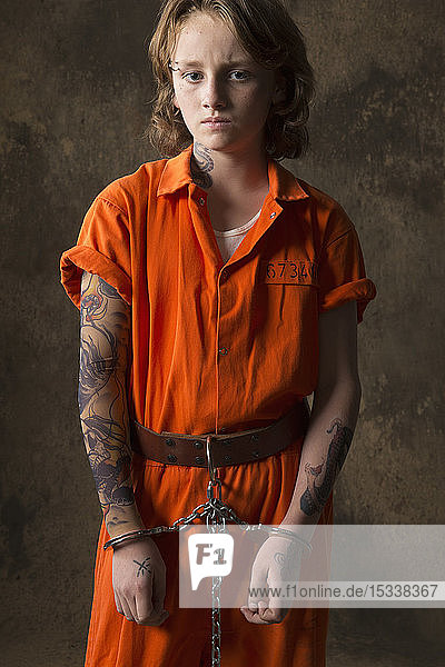 Junge in Häftlingsanzug und Handschellen