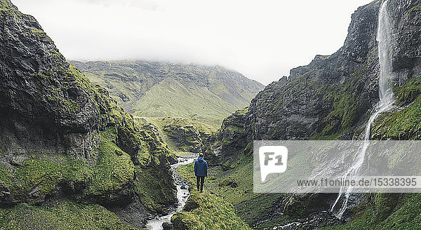 Mann beim Wandern an einem Wasserfall in Island