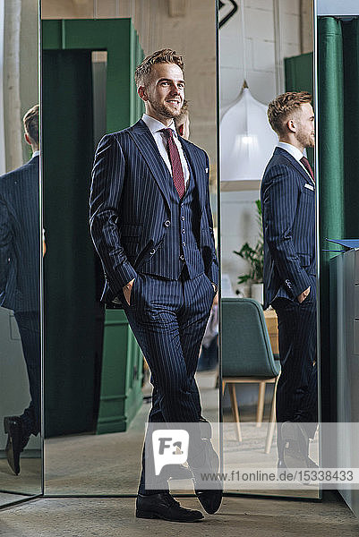 Smiling man wearing pinstripe suit by mirrors